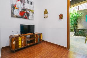 a living room with a tv on a wooden entertainment center at Villa Moringa 2 - Private Villa in the Heart of Canggu, 5 Minutes from the Beach in Canggu