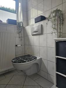 a bathroom with a toilet with a black seat at La Casa in Medebach