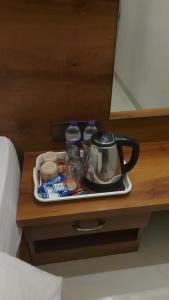 a tray with a tea kettle on a table next to a bed at Aarvis House in Mahabaleshwar