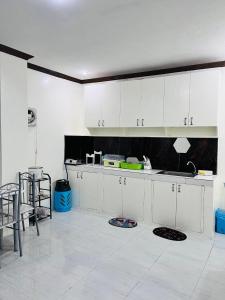 a kitchen with white cabinets and a white tile floor at M and M Apartment in Surigao +50 photos