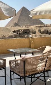 een tafel en stoelen met uitzicht op de piramides bij Tamara Pyramids View in Caïro