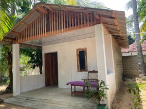 una pequeña casa con un banco púrpura delante de ella en Feel Like Home Arugam Bay, en Arugam Bay 3 fotos más