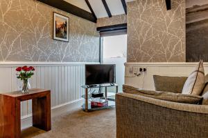 Dale View Cottages and Rooms - Whitby في Stainsacre: غرفة معيشة مع أريكة وتلفزيون