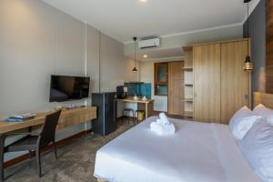 a hotel room with a bed and a desk and a television at Atania Apartment in Jimbaran