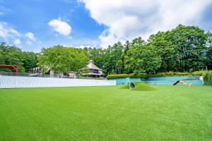 a large yard with green grass and a pool at Wan Wan Paradise Yatsugatake in Hokuto