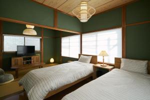 two beds in a room with green walls and windows at 民泊あまやど Amayado in Owase