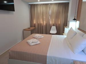 a bedroom with a large bed with two towels on it at Perla Beach in Agia Marina Nea Kydonias
