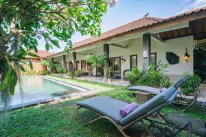a lounge chair in front of a house with a swimming pool at Villa Moringa 1 - 3 Bedrooms Villa in Canggu Central in Canggu