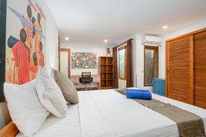 a bedroom with a large white bed with a painting on the wall at Villa Moringa 1 - 3 Bedrooms Villa in Canggu Central in Canggu +49 photos