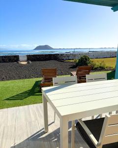 a white table and chairs on a patio with the ocean at BeachFront Villa - La Casa del Mar in Corralejo