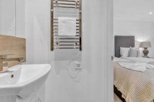 - une salle de bains blanche pourvue d'un lavabo et d'un lit dans l'établissement Central Snug with Patio By My Getaways, à Worthing 11 autres photos