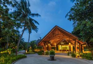 a resort with a wooden building with palm trees at Dusit Thani Maldives in Baa Atoll