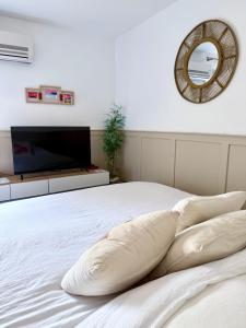 ein Schlafzimmer mit einem weißen Bett und einem Spiegel in der Unterkunft Appart proche plage, idéal et tranquille, parking privé - arrivée autonome - lit queen size in La Seyne-sur-Mer