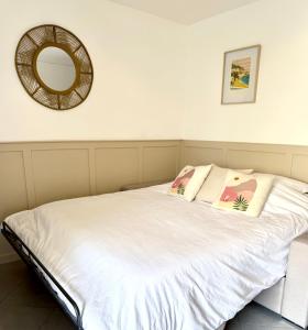 ein weißes Bett mit Kissen und einem Spiegel an der Wand in der Unterkunft Appart proche plage, idéal et tranquille, parking privé - arrivée autonome - lit queen size in La Seyne-sur-Mer + 30 Fotos