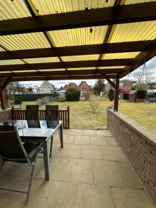 a patio with a table and chairs under a wooden pergola at Ferienhaus Heidetraum Lüneburger Heide in Munster im Heidekreis