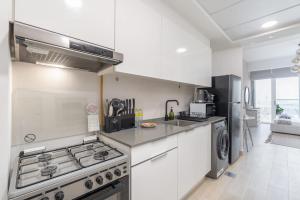 Una cocina blanca con estufa y refrigerador. en An Exceptional Studio in JVC that Sleeps 2!, en Dubái