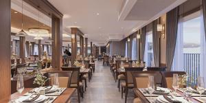 a restaurant with wooden tables and chairs and windows at Paradise Legacy Cruise Halong in Ha Long