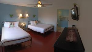a room with two beds and a table and a tv at El Rancho Motel in Bishop