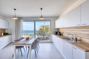 a kitchen with white cabinets and a table with chairs at Blu Mar Sea View Apartments in St Paul's Bay