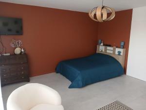 a bedroom with a blue bed and a white chair at La Cabine du Man, meublé de tourisme classé 2 étoiles in Roscoff