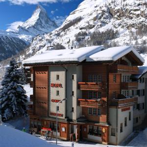 um hotel nas montanhas com neve no telhado em Hotel Cheminee em Zermatt