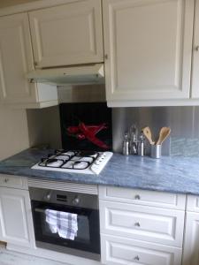 a kitchen with white cabinets and a stove top oven at Les 3 vallées 1 in Séranon