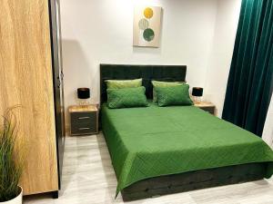 a bedroom with a green bed with two night stands at Uranus view Apartament in Tunari +4 photos