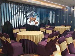a room with tables and chairs and a painting of a deer at Hotel YKM Crown in Dehradun