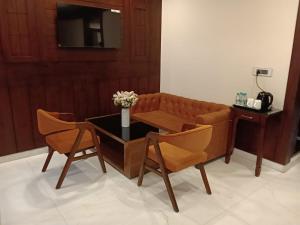 a living room with a couch and a table and chairs at Hotel YKM Crown in Dehradun