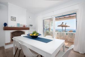 a white dining room with a table and a view of the ocean at Domus Alba A in Portocolom