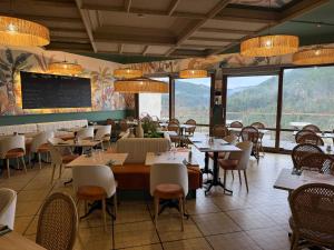 a dining room with tables and chairs and windows at Hôtel Des Rochers in Marvejols
