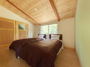 安曇野市にあるAMBIENT 安曇野コテージの木製の天井のある部屋にある大きなベッド