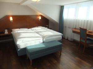 a bedroom with a large white bed and a table at Hotel Hecht Appenzell in Appenzell