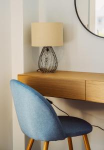 a blue chair sitting next to a desk with a lamp at K&E Guesthouse in Preveza