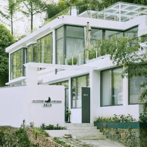 a white house with glass windows at Moganshan Qingyue Banxia Hot Spring Resort in Jimiaowu