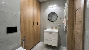 a bathroom with a sink and a clock on the wall at NEW Apartament BLACK Warszawa Parking FREE in Wola Mrokowska +17 photos
