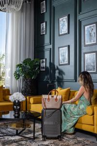 Una mujer sentada en un sofá amarillo con una maleta. en Yin Hotel & Spa, en Marrakech 236 fotos más