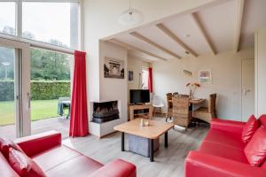a living room with a red couch and a table at Kraanvogel I Fraaie bungalow met mooie grote tuin in Zwiggelte