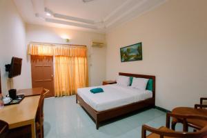 a hotel room with a bed and a desk and a table at Dewi Ratih Hotel Batang in Batang
