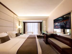 a hotel room with a large bed and a flat screen tv at Regal Kowloon Hotel in Hong Kong