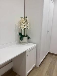 a white table with a vase with flowers on it at Sorrento Bay Apartment in Sorrento +7 photos