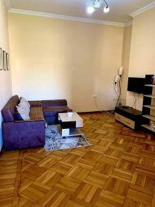 a living room with a purple couch and a wooden floor at Central apartments in Kutaisi