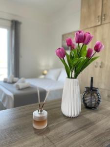 a white vase with purple flowers on a table at Roomie Studio Near PAGNI in Goúrnes