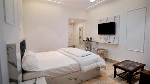 a white bedroom with a bed and a flat screen tv at Felicia Meadows in Dhanaulti