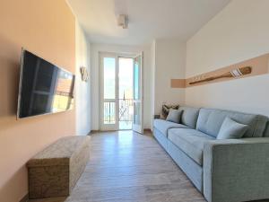 Una sala de estar con un sofá azul y un televisor. en Ama Homes - Balcony Lakeview, en Bellagio