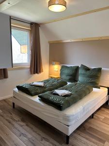 a bed with green pillows on it in a room at Urlaub am Schwarzbach mit Sauna und Whirlpool Haus Johanna in Butgenbach