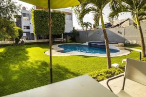 a backyard with a pool and palm trees and an umbrella at Collection O Hotel Mango,Six Flags Hurricane Harbor Oaxtepec in Oaxtepec