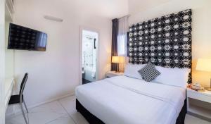 a bedroom with a white bed with a black and white headboard at Best Western Regency Suites in Tel Aviv