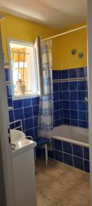 een blauw betegelde badkamer met een bad en een wastafel bij Maison Gorges du Gardon in Collias