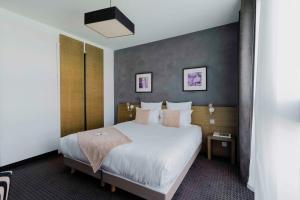 a hotel room with a large bed with white sheets at Best Western Hôtel De La Cité & Spa in Guérande +27 photos